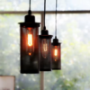 Pendente industrial em metal preto suspenso em ambiente de pé-direito alto, estilo loft.