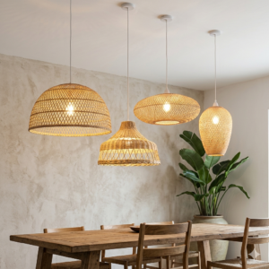 Quatro luminárias pendentes de vime trançado penduradas sobre uma mesa de jantar rústica de madeira em uma sala com parede de cimento queimado.